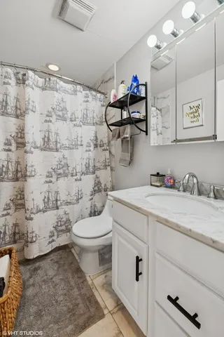 a bathroom with a granite countertop toilet sink and mirror