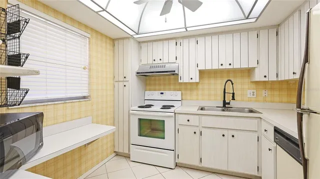 a kitchen with granite countertop white cabinets and white appliances