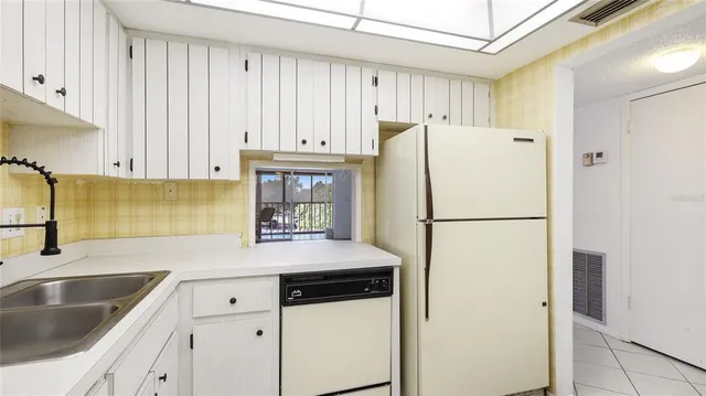 a white refrigerator freezer sitting in a kitchen with stainless steel appliances granite countertop white cabinets and a refrigerator