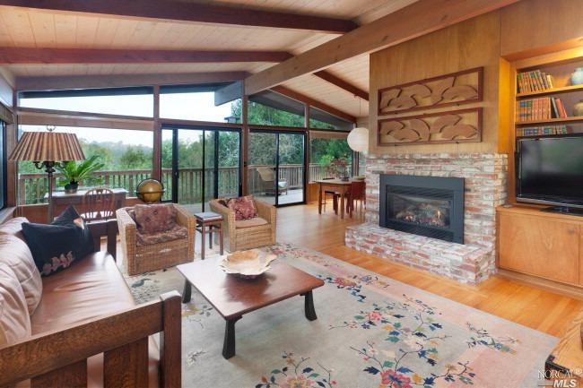 a living room with furniture a fireplace and a floor to ceiling window next to a yard