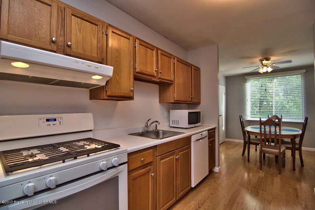 1211 Summit Pointe Scranton, PA 18508 - Photo 6 of 33 a kitchen with stainless steel appliances a stove a sink dishwasher and a dining table with cabinets
