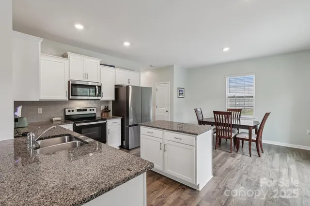 a kitchen with stainless steel appliances granite countertop a sink stove and microwave