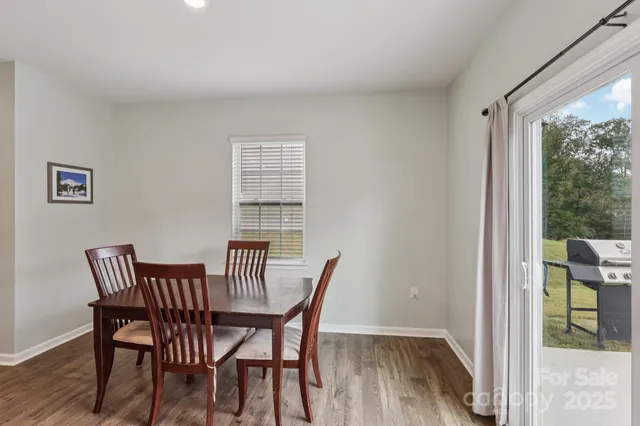 a kitchen with stainless steel appliances granite countertop a dining table chairs and a refrigerator