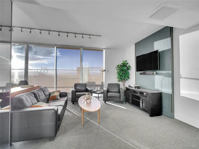 a living room with furniture a flat screen tv and floor to ceiling window