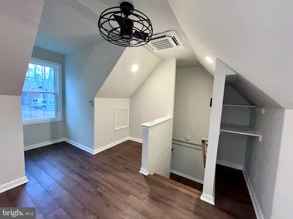 an empty room with wooden floor a ceiling fan and windows