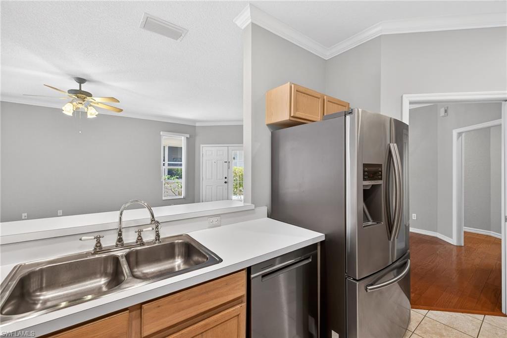 599 Crossfield Circle, Unit 35 Naples, FL 34104 - Photo 13 of 26 Kitchen featuring ornamental molding, stainless steel appliances, light countertops, ceiling fan, and light wood finish cabinetry