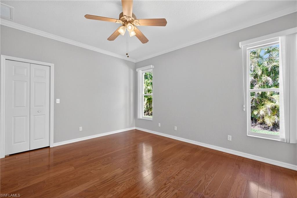599 Crossfield Circle, Unit 35 Naples, FL 34104 - Photo 14 of 26 Unfurnished bedroom with ornamental molding, dark wood-type flooring, ceiling fan, and a closet