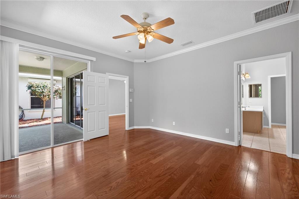 599 Crossfield Circle, Unit 35 Naples, FL 34104 - Photo 16 of 26 Unfurnished bedroom featuring hardwood / wood-style flooring, access to exterior, crown molding, ceiling fan, and ensuite bathroom