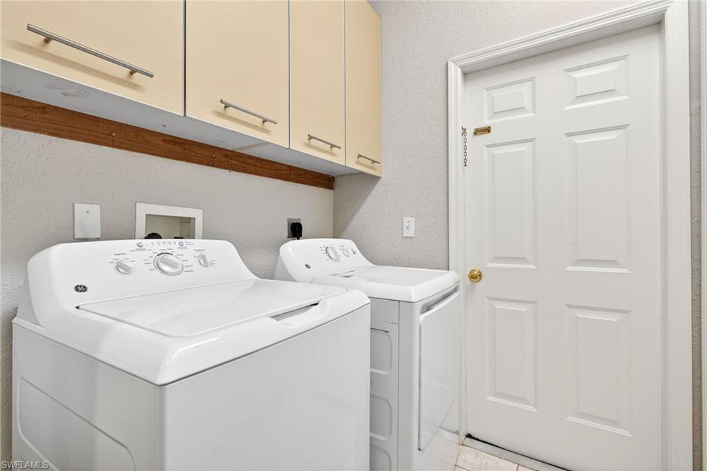 599 Crossfield Circle, Unit 35 Naples, FL 34104 - Photo 23 of 26 Laundry area featuring a textured wall, independent washer and dryer, and cabinet space