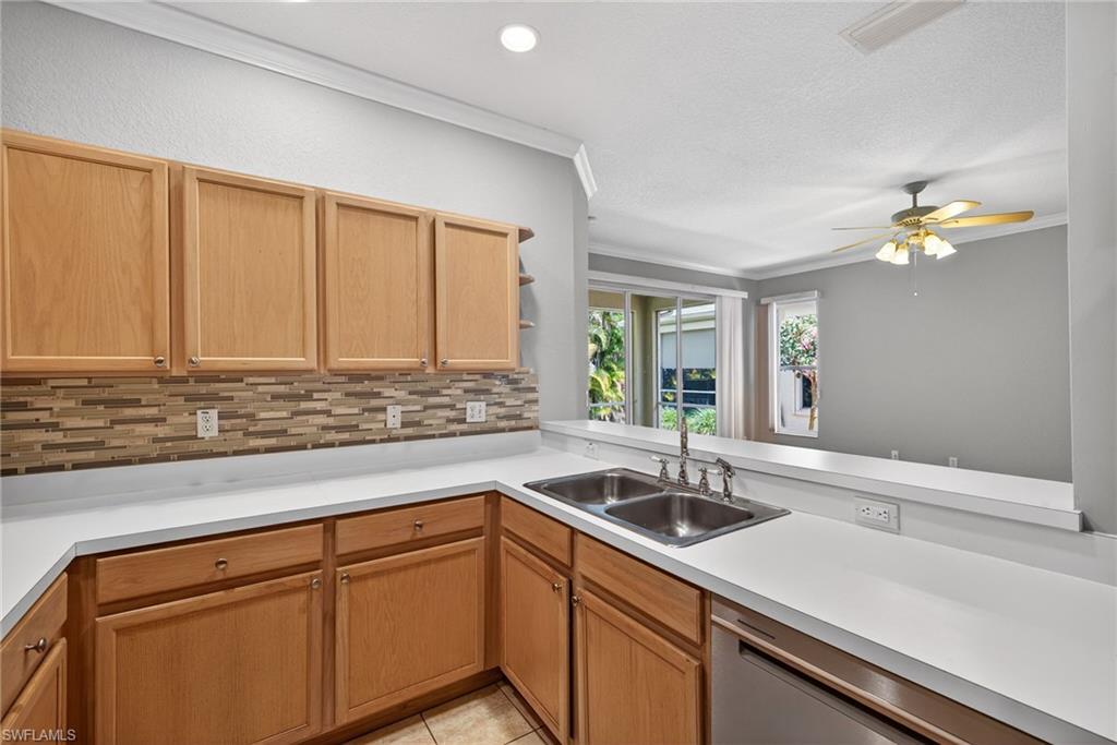 599 Crossfield Circle, Unit 35 Naples, FL 34104 - Photo 10 of 26 Kitchen with crown molding, light countertops, backsplash, a ceiling fan, and stainless steel dishwasher