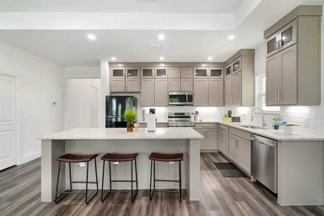 a kitchen with stainless steel appliances granite countertop a table chairs sink and cabinets