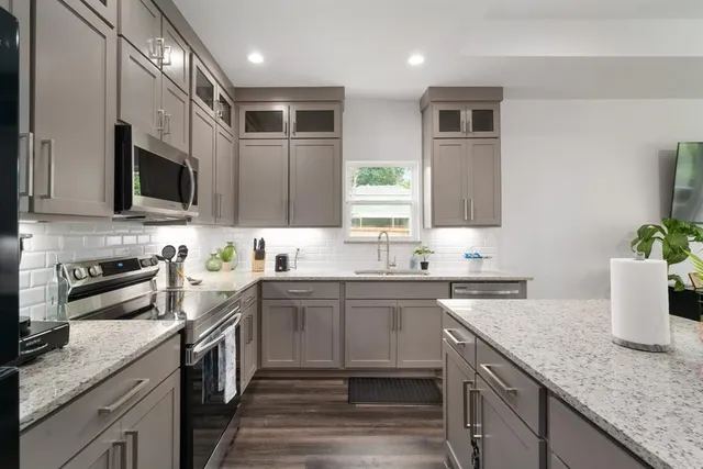 a kitchen with stainless steel appliances granite countertop a sink a stove top oven a refrigerator and dishwasher with wooden floor