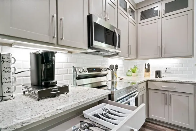 a kitchen with stainless steel appliances a stove microwave and sink