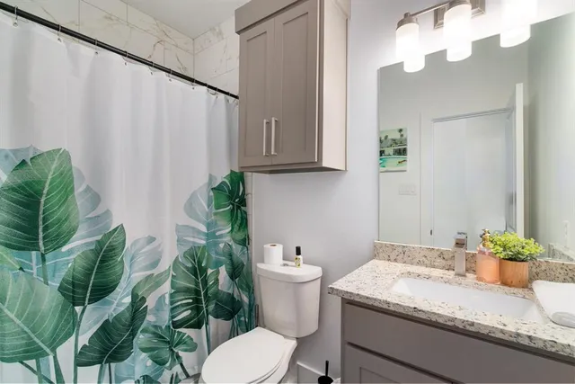 a bathroom with a granite countertop sink a toilet and a mirror
