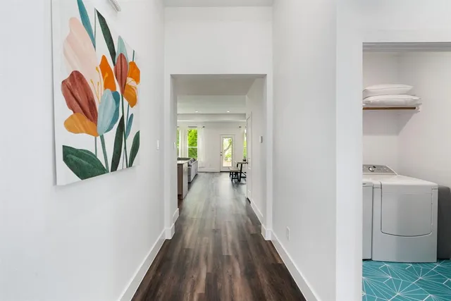 a view of a hallway with wooden floor and a bathroom