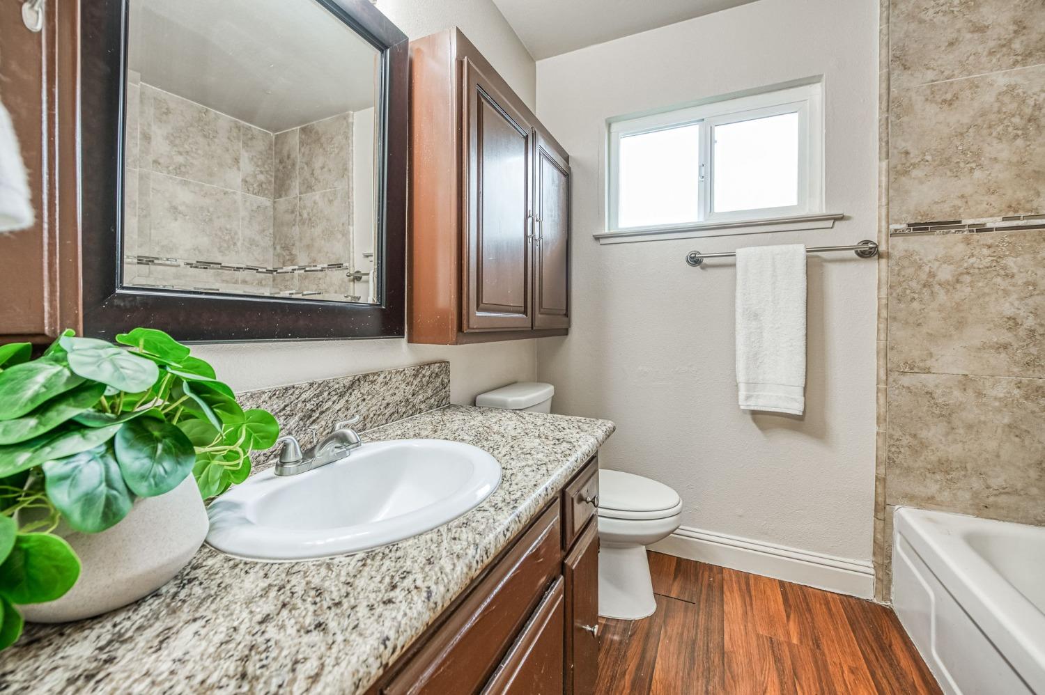 2866 Caesar Avenue Clovis, CA 93612 - Photo 22 of 45 a bathroom with a granite countertop sink a toilet and a mirror