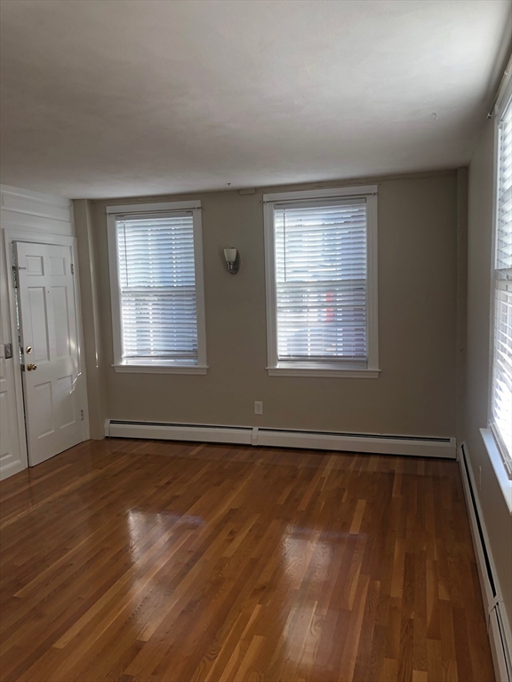 28 Darling Street, Unit 3 Marblehead, MA 01945 - Photo 3 of 8 an empty room with wooden floor and windows