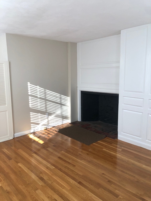 28 Darling Street, Unit 3 Marblehead, MA 01945 - Photo 4 of 8 a view of empty room with wooden floor and fireplace