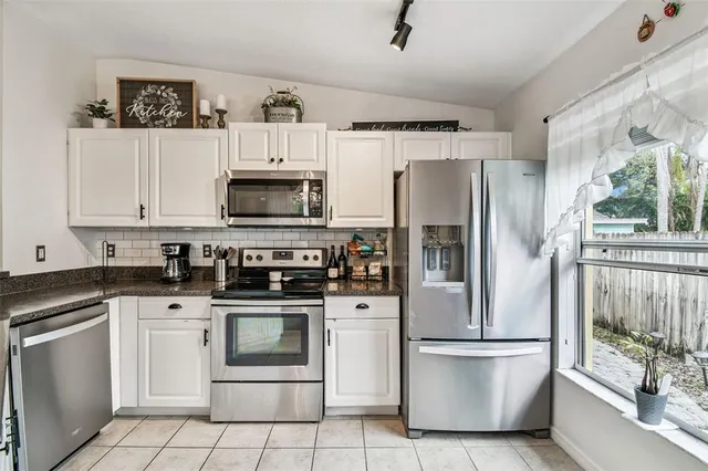 a white kitchen with stainless steel appliances and white cabinets