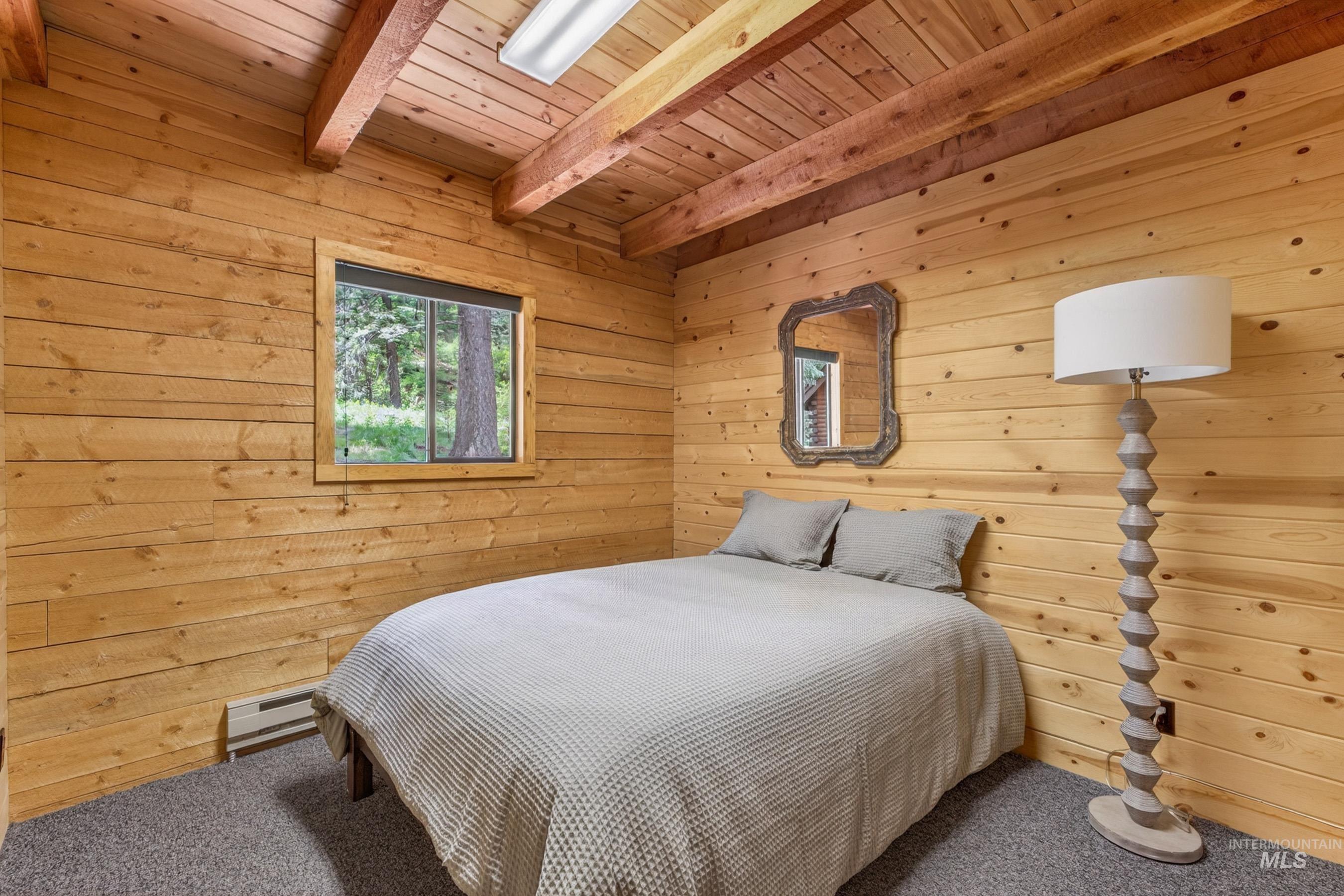 2339 West Mountain Road Donnelly, ID 83615 - Photo 13 of 37 Knotty pine paneling, wood-beamed ceiling, and a grey carpeted floor