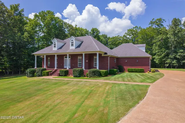 a front view of a house with a yard and trees