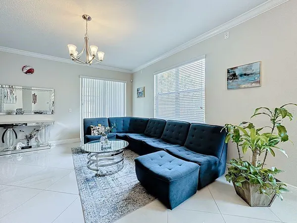a living room with furniture a chandelier and a flat screen tv