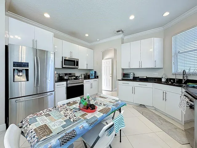 a kitchen with granite countertop stainless steel appliances a refrigerator stove microwave and cabinets