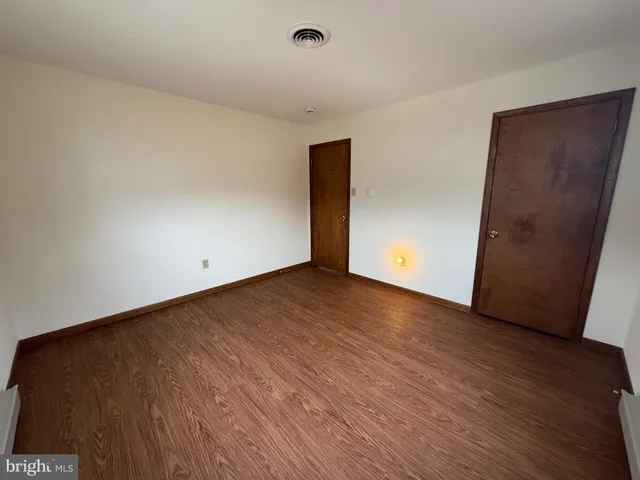 a view of an empty room with wooden floor and closet