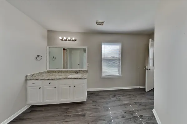 a room with granite countertop a sink and a mirror