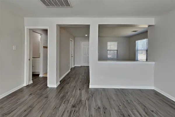 a view of a hallway with wooden floor and a living room
