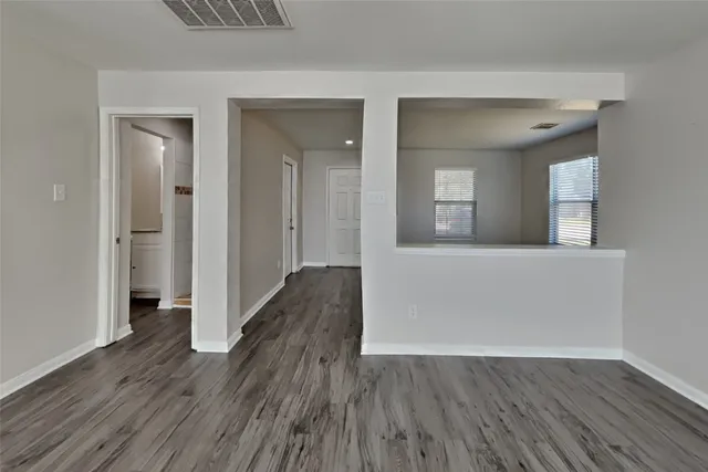a view of a hallway with wooden floor and a living room
