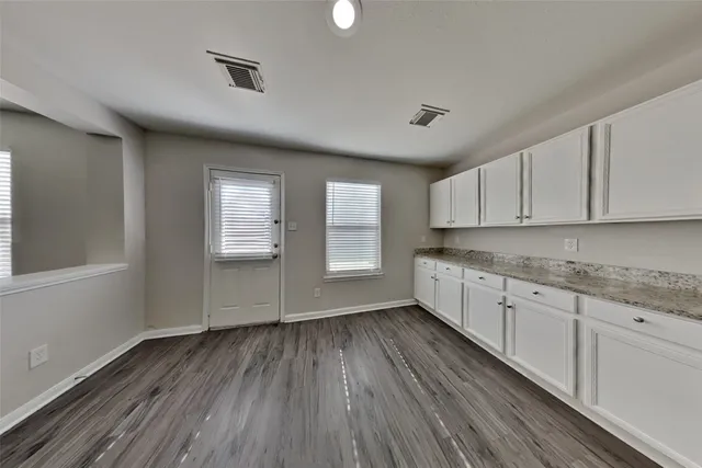 a kitchen with granite countertop wooden floors a sink and a window