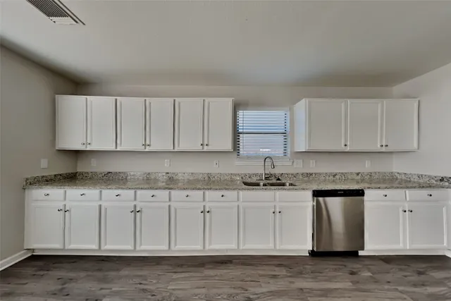 a kitchen with granite countertop white cabinets and a sink