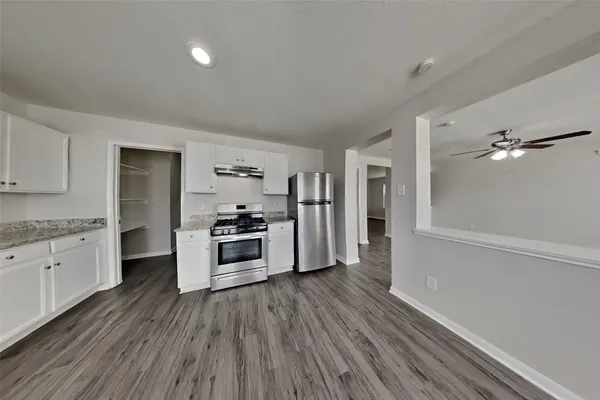 a kitchen with granite countertop a refrigerator and a stove top oven