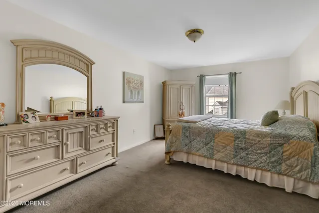a spacious bedroom with a bed a dresser and windows