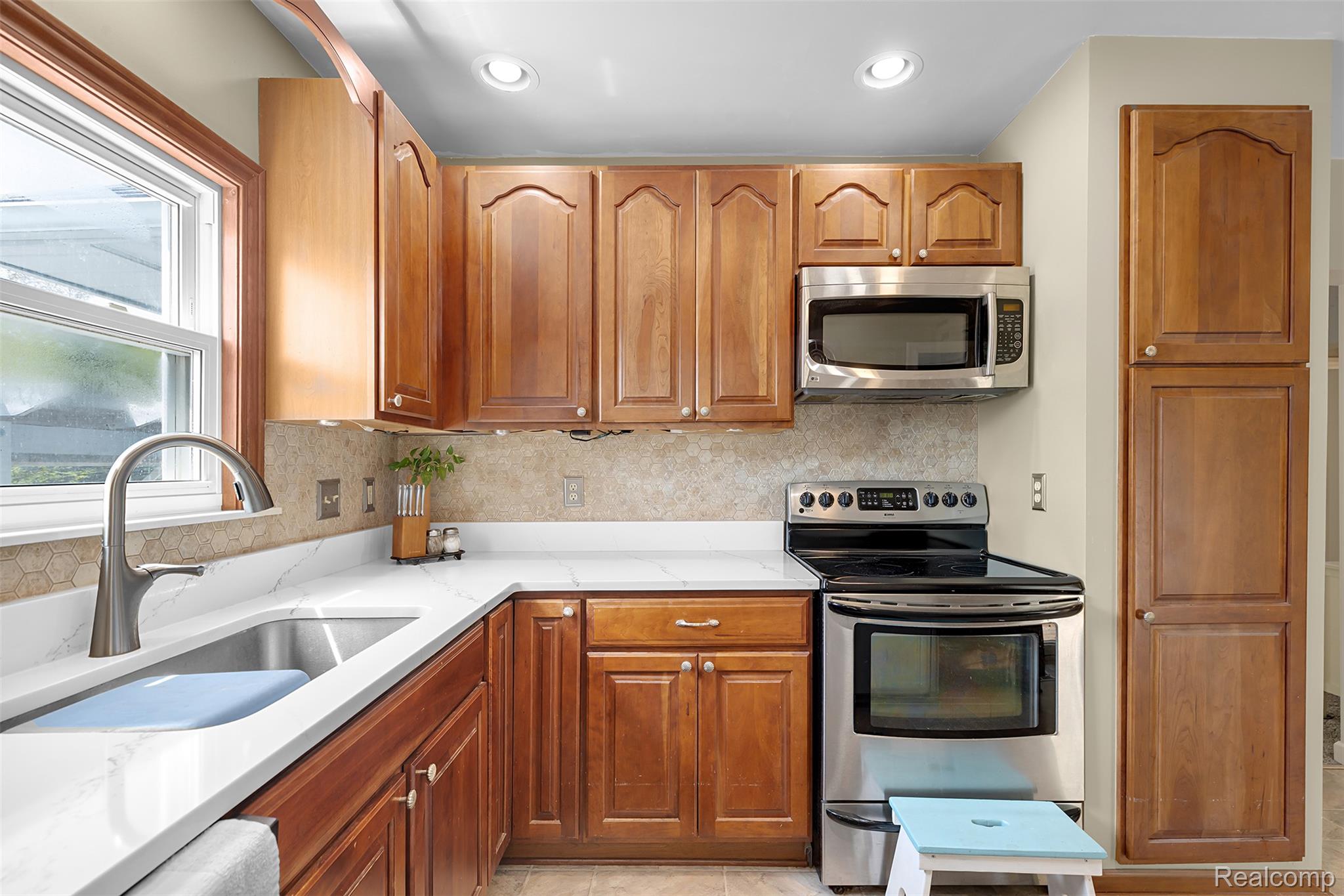 22827 Meridian Road Grosse Ile, MI 48138 - Photo 24 of 36 Kitchen featuring stainless steel appliances, light stone counters, wood finish cabinets, and tasteful backsplash