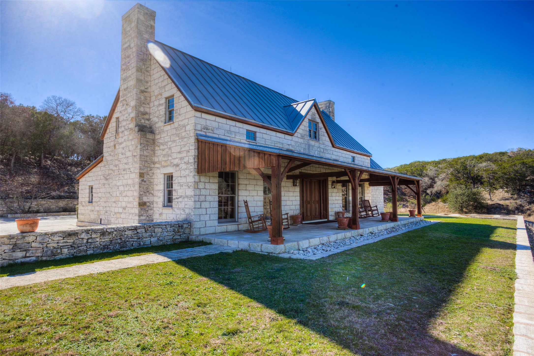 3777 Middle Creek Road Blanco, TX 78606 - Photo 9 of 40 Front of home with a chimney, a standing seam roof, a yard, covered porch, and stone siding