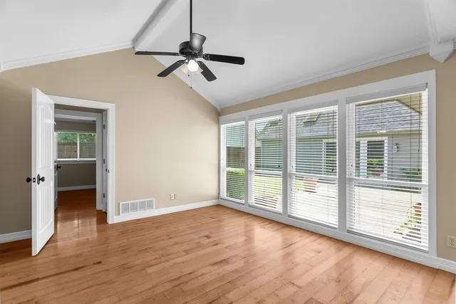 a view of an empty room with a window and wooden floor