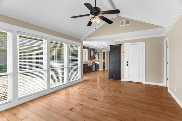 a view of empty room with wooden floor and fan