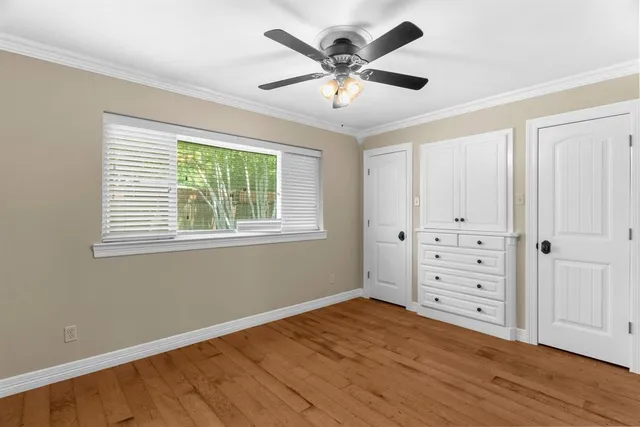a big room with wooden floor a chandelier fan and windows