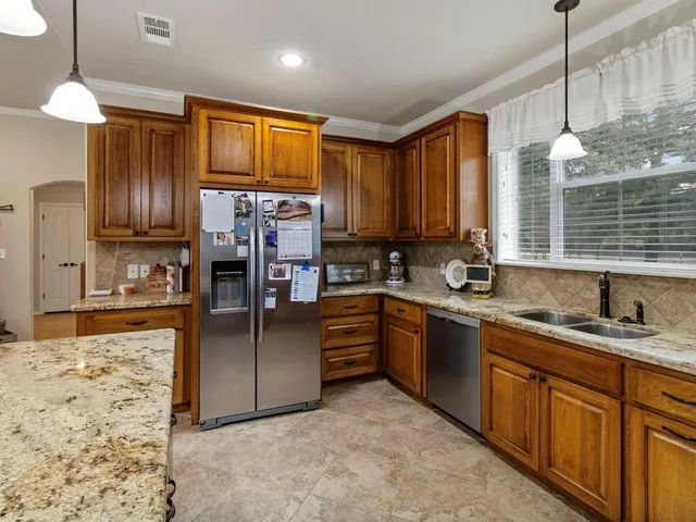 a kitchen with stainless steel appliances kitchen island granite countertop a sink refrigerator and cabinets