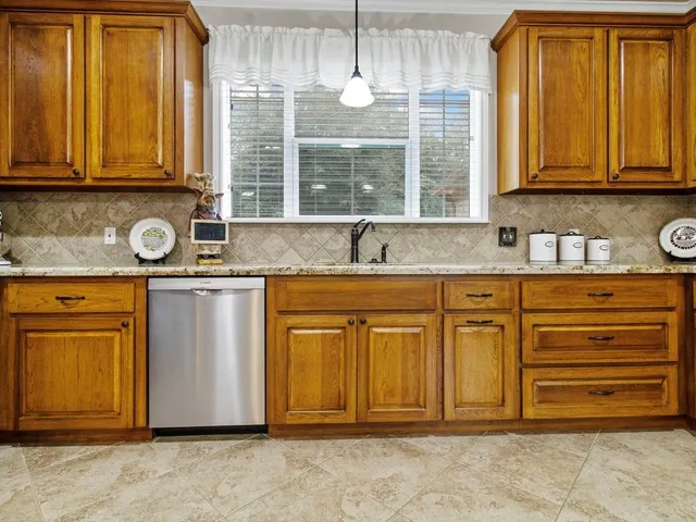 a kitchen with granite countertop cabinets sink and window