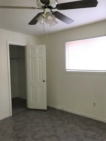 an empty room with a ceiling fan and a window