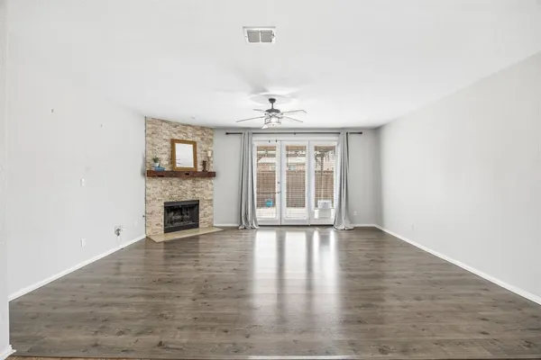 an empty room with wooden floor fireplace and windows