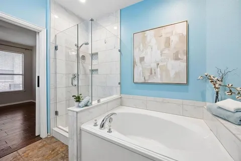 a bathroom with a tub a potted plant and a shower