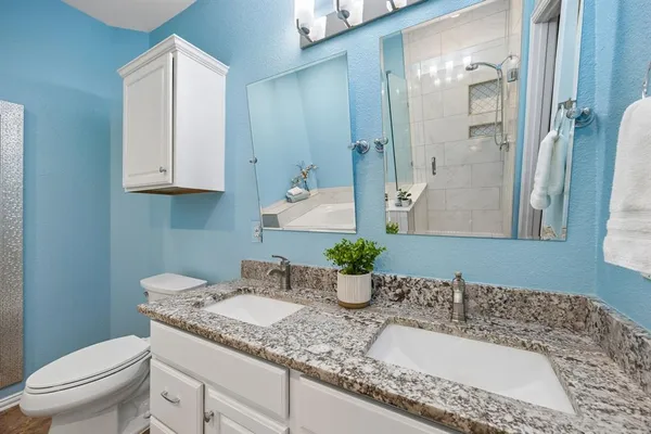 a bathroom with a granite countertop sink a toilet and mirror