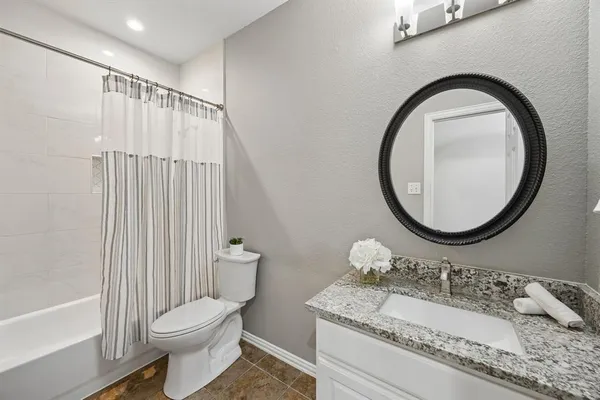 a bathroom with a granite countertop sink mirror vanity and a toilet