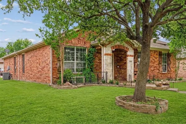 a front view of a house with garden and tree