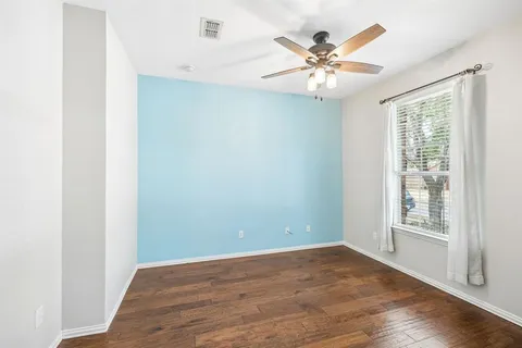 an empty room with wooden floor and ceiling fan