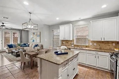 a kitchen with granite countertop sink stove and white cabinets